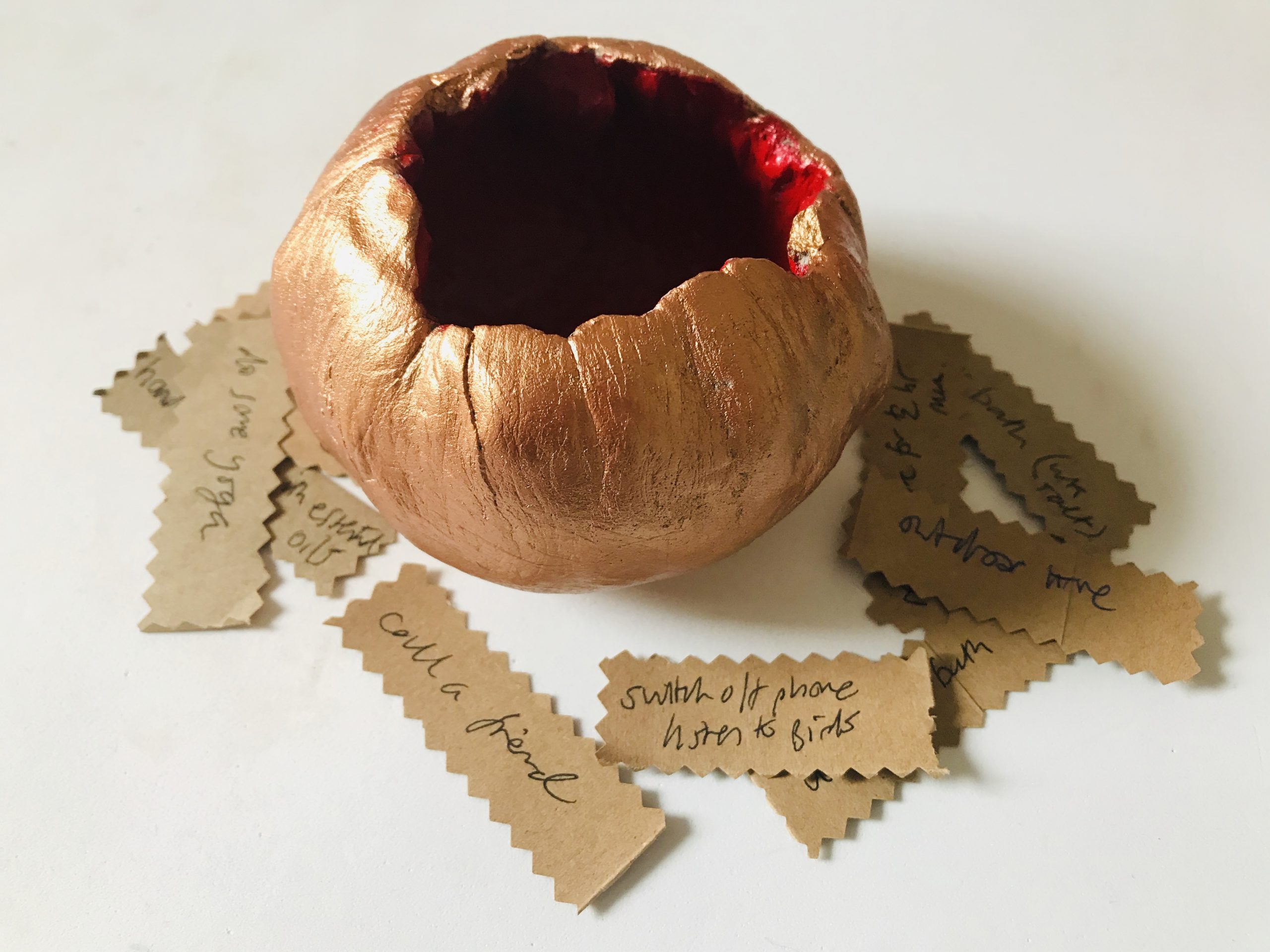 a bronze-coloured clay vessel surrounded by messages on small pieces of paper