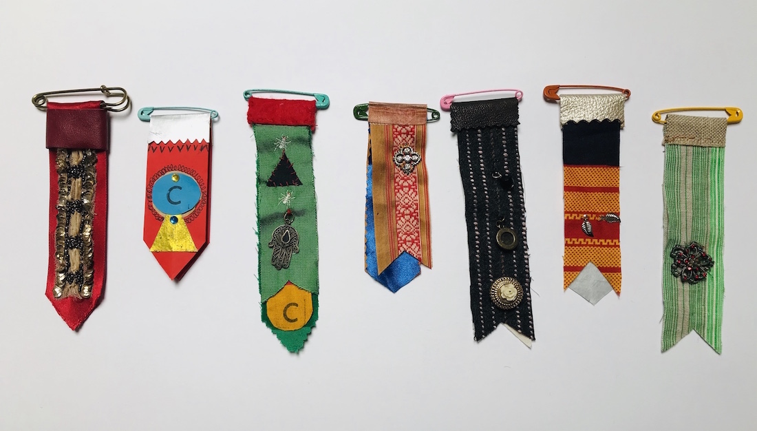 colourful strips of textiles attached to large safety pins to create impromptu 'medals'