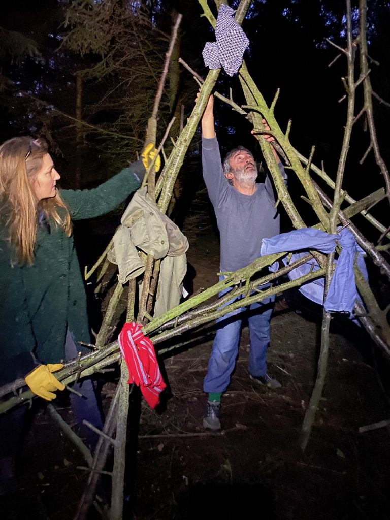 two people building a structure with alder poles