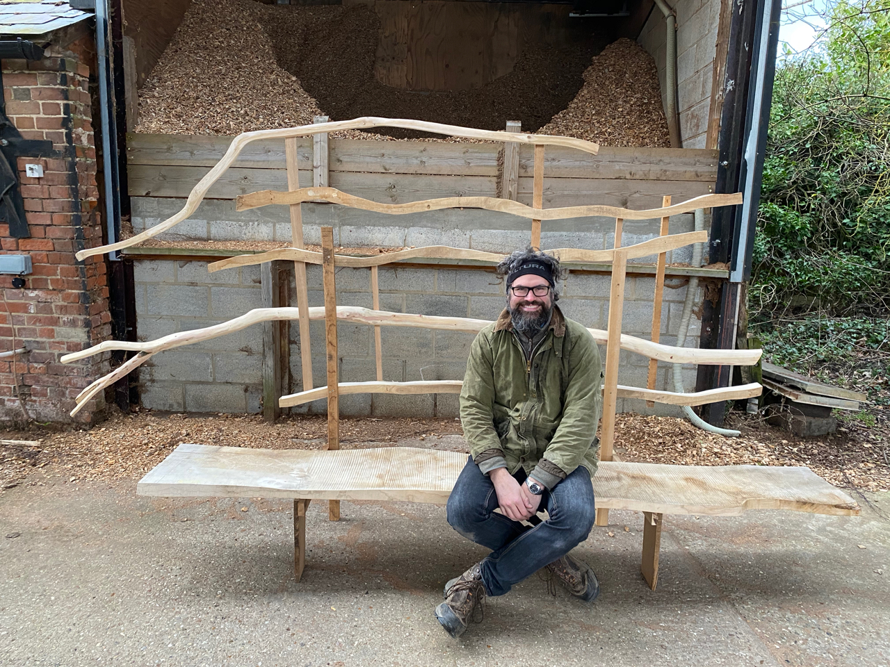 a man sitting on a large bench made from green wood