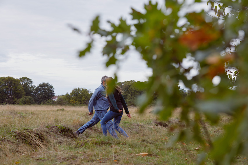 two people, moving close together in a grassy landscape