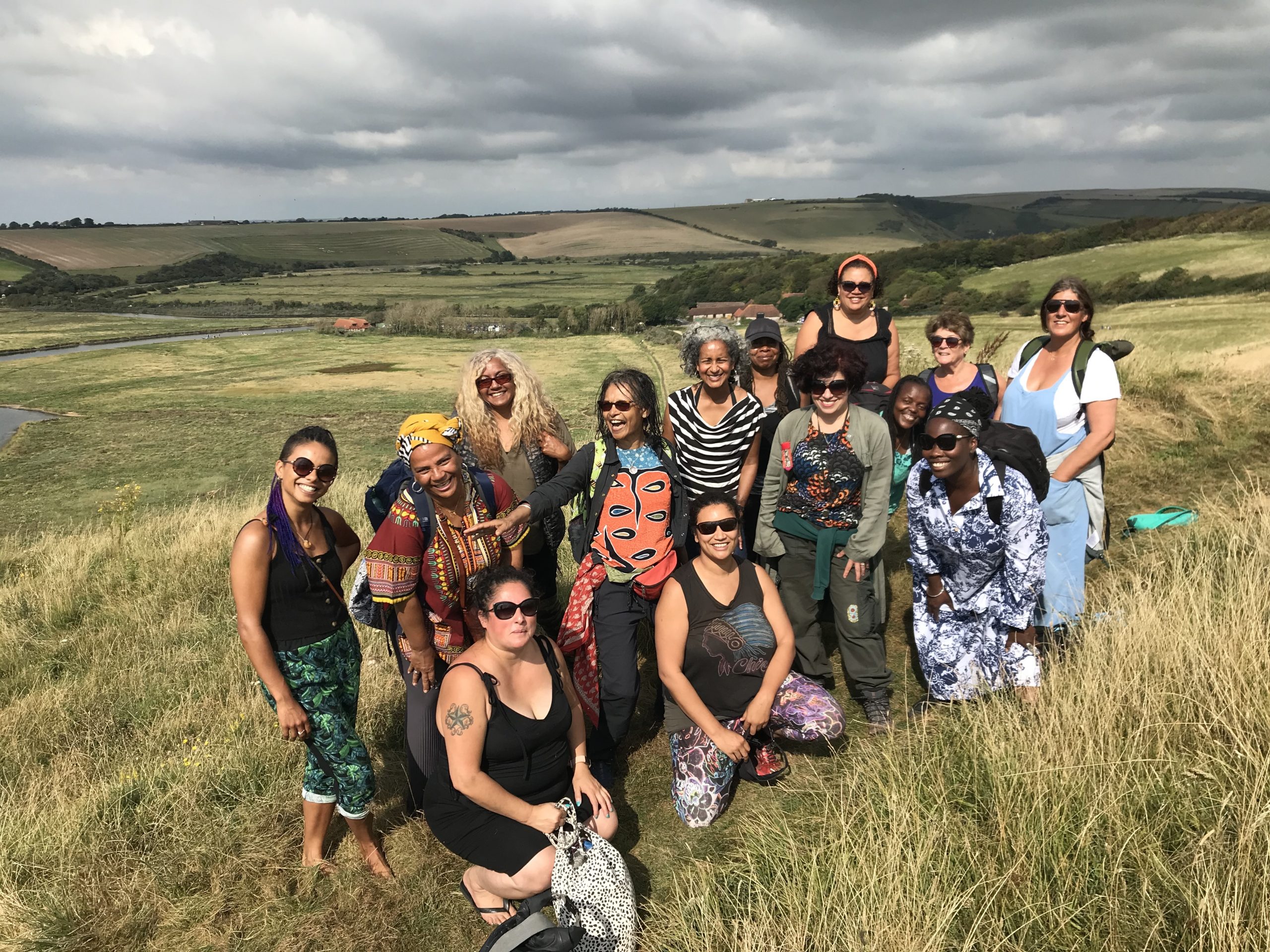 A group of black, brown and women of colour smiling for the camera in a rural landscape